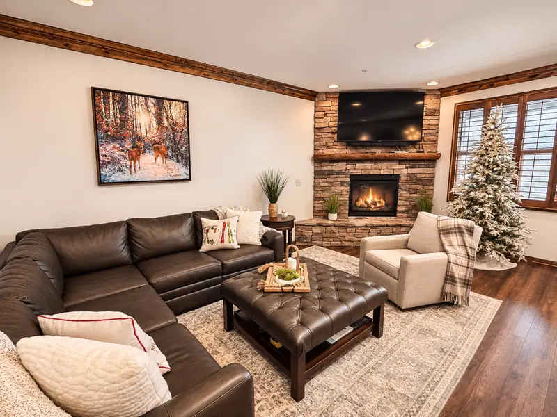 Leather sectional and ottoman in the Black Bear 32 living room, facing the stone fireplace