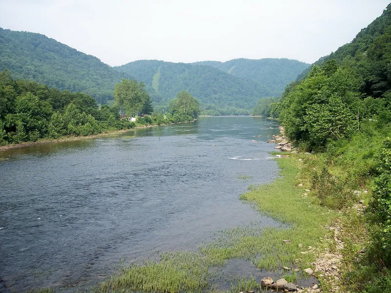 The wide, calm Cheat River at Rowlesburg, between green wooded hills