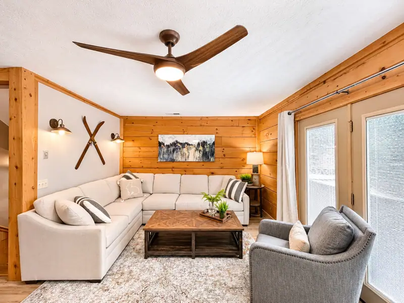Living room at Loggers Run 12 with a white sectional, crossed skis and a ceiling fan