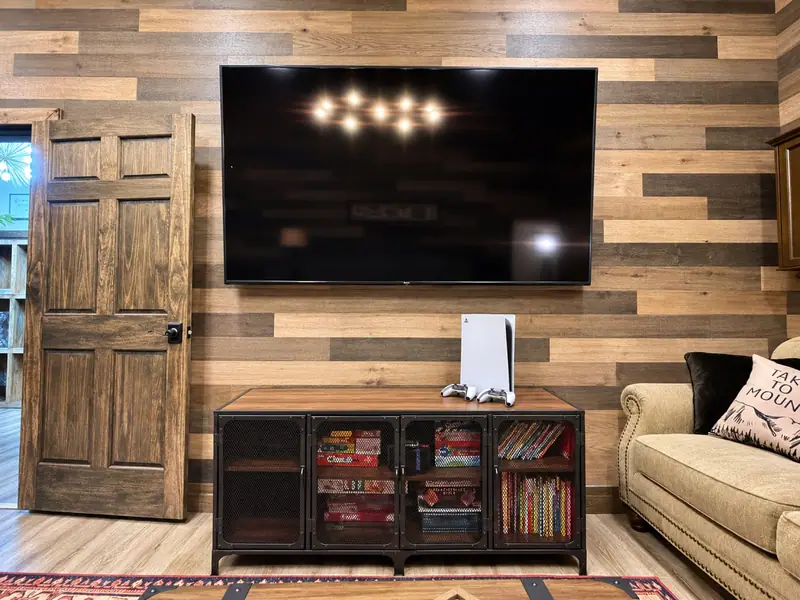 Rec room at Loggers Run 12 with an 85-inch TV and a PS5 on a wood and iron console