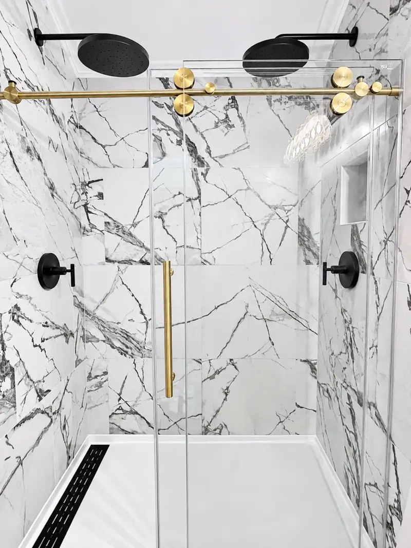 Walk-in glass shower with marble tile and brass fixtures in the renovated Loggers Run 12 primary bath