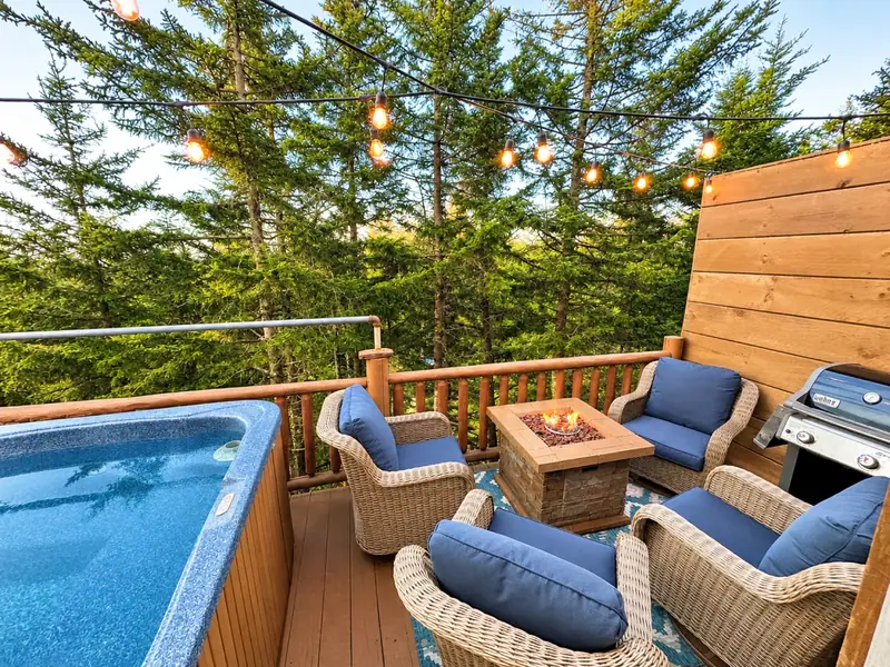 Private hot tub, fire table and wicker seating on the Loggers Run 12 deck in summer