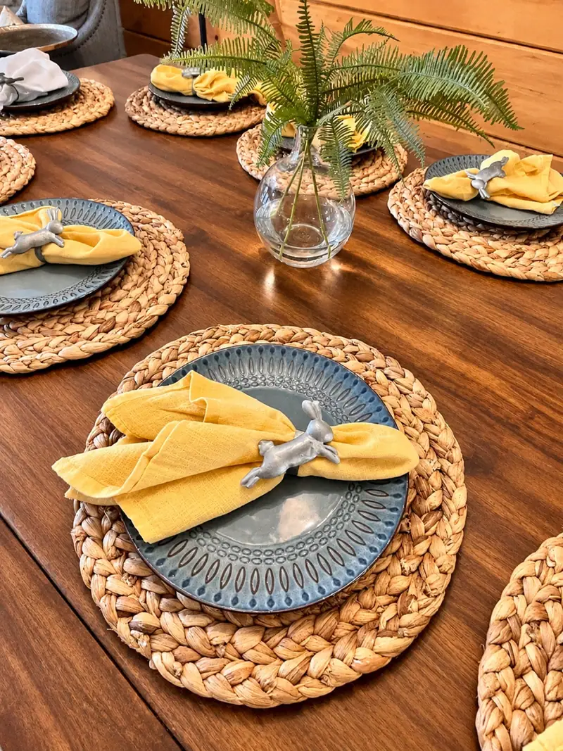 Place settings with woven chargers on the Loggers Run 12 dining table