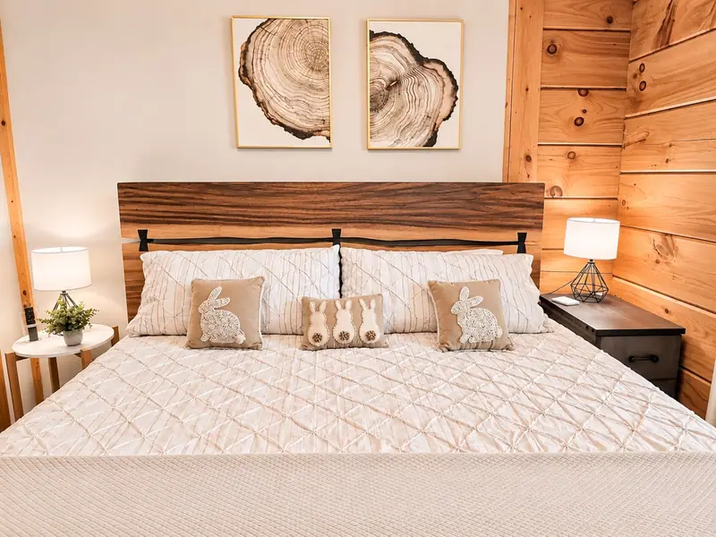 King bed at Loggers Run 12 with a wood headboard under two tree-ring prints