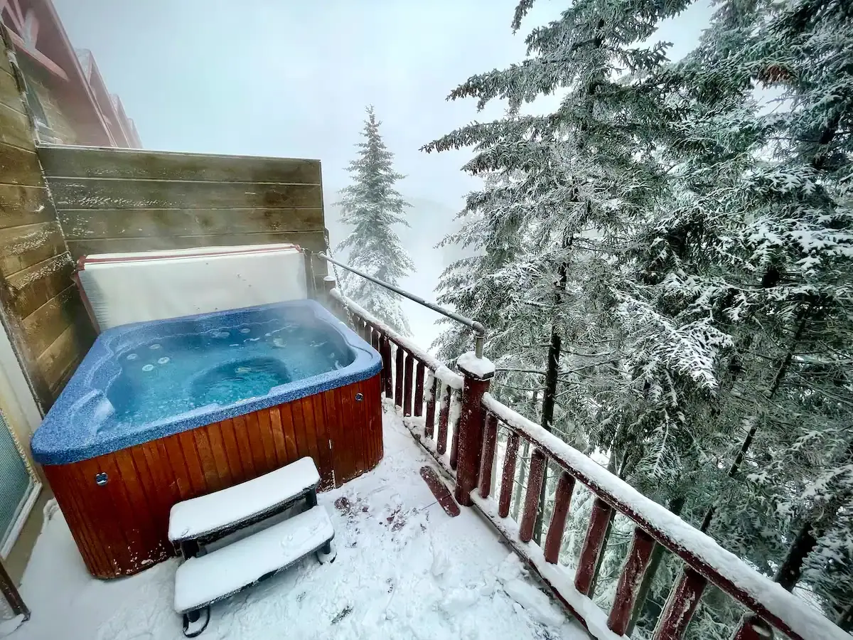 Private hot tub at Loggers Run 16 under snowy spruce