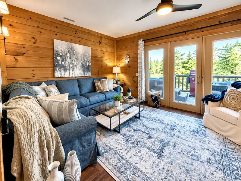 Blue sectional and doors to the deck in the Loggers Run 16 living room