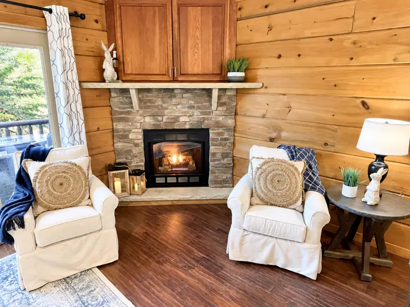 Two white armchairs facing the stone gas fireplace at Loggers Run 16