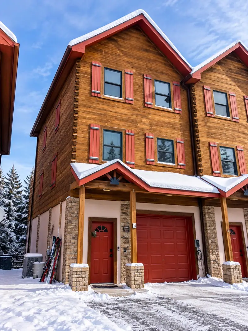 Front of the Loggers Run 16 townhome in winter, with red garage doors and snow on the eaves