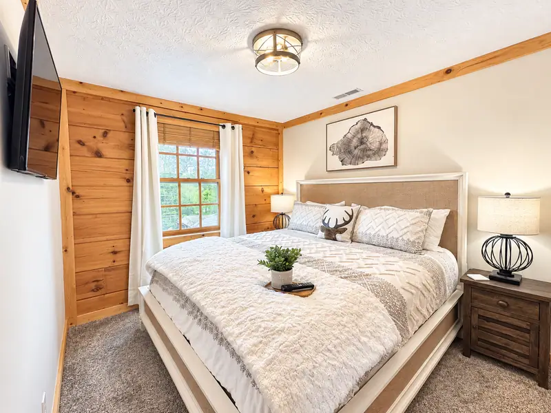 King bedroom at Loggers Run 4 with log walls, white bedding and a wall TV