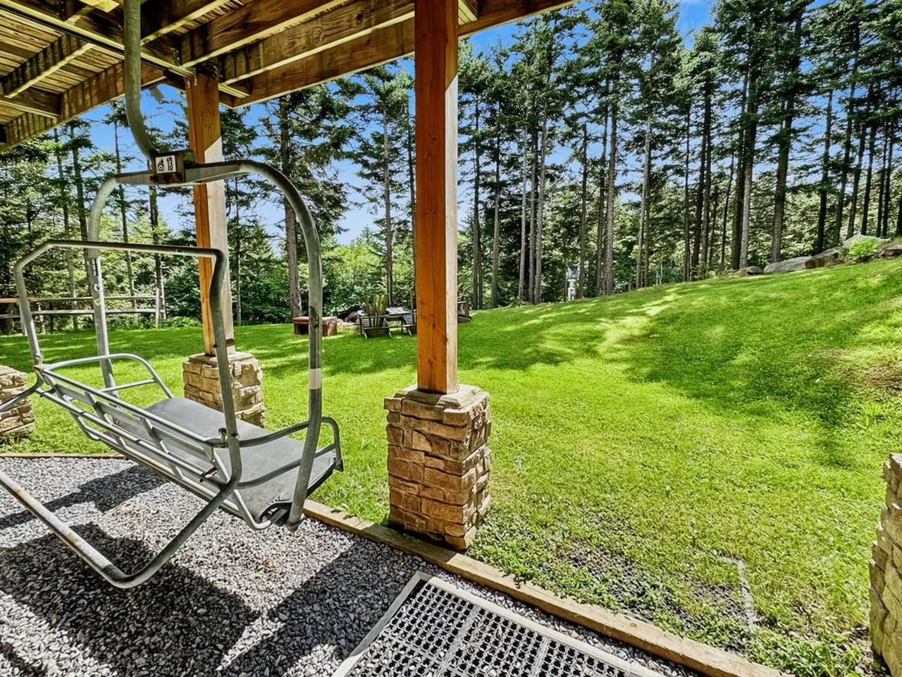 Covered back porch at Loggers Run 4 opening onto a green lawn and spruce