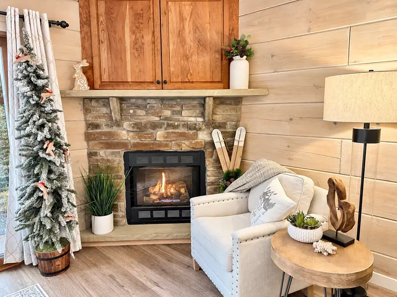 Stone gas fireplace at Loggers Run 4 with a white armchair and a snowy little tree