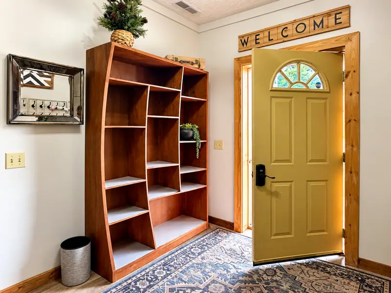 Entry at Loggers Run 4 with a green front door, bookshelf and welcome sign