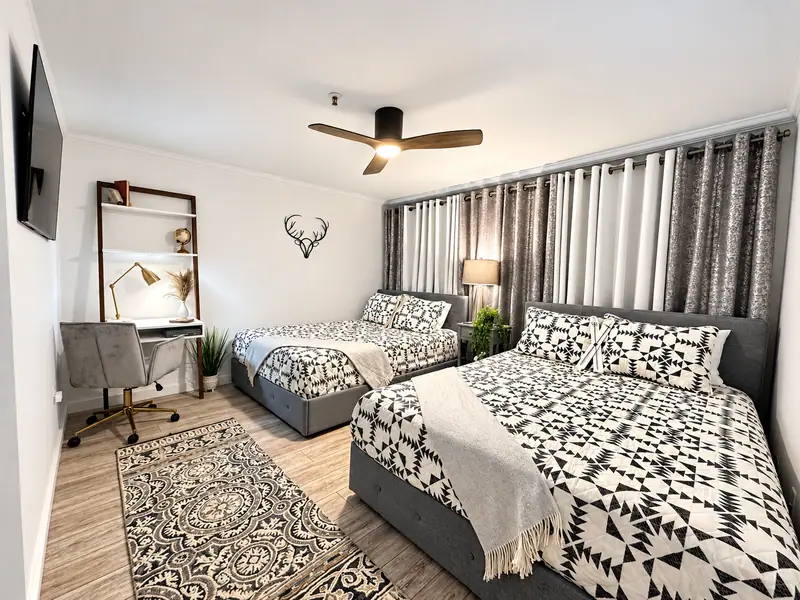 Bedroom at Mountain Lodge 114 with two beds, a desk and a ceiling fan