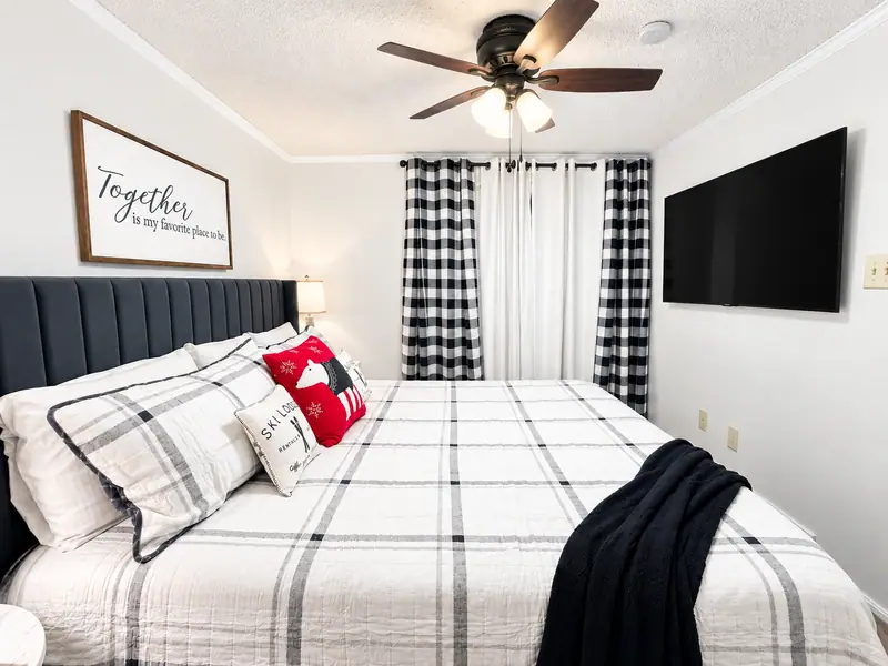 Bedroom at Mountain Lodge 140 with buffalo check curtains and a wall TV