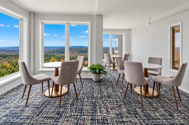 Seating area at Mountain Lodge with fall foliage through the windows