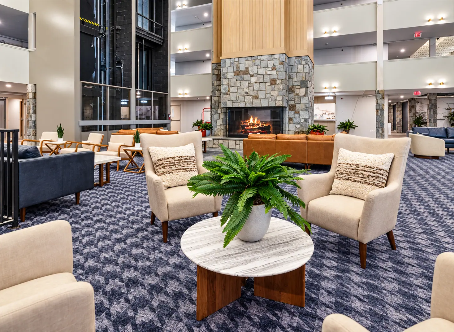 Mountain Lodge lobby seating with armchairs, a stone fireplace, and the atrium above