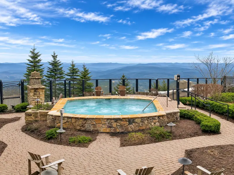 The Seneca courtyard hot tub on a summer day, with Adirondack chairs and long ridge views