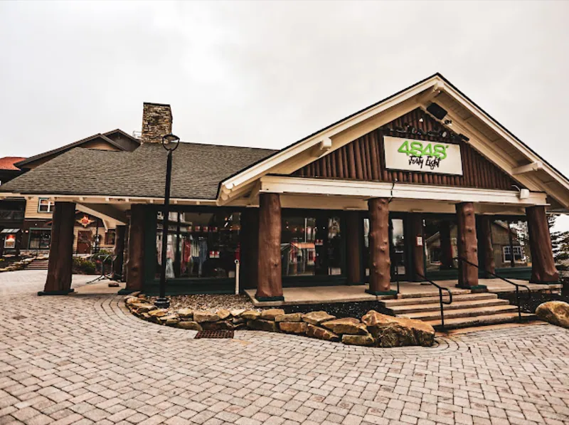 The 4848 storefront in the Snowshoe Village, with log posts and a stone walk