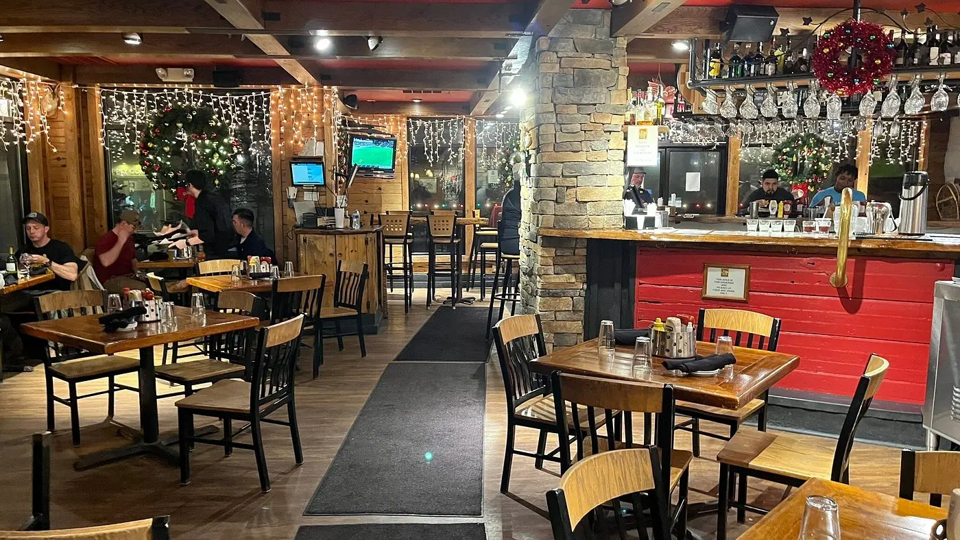 The dining room at Foxfire Grille, with a red bar, wood tables, and holiday lights
