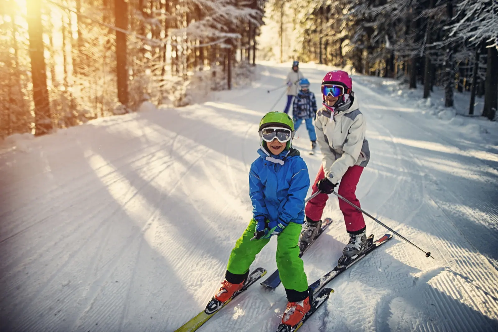 Two young skiers in bright jackets on a sunny groomed trail