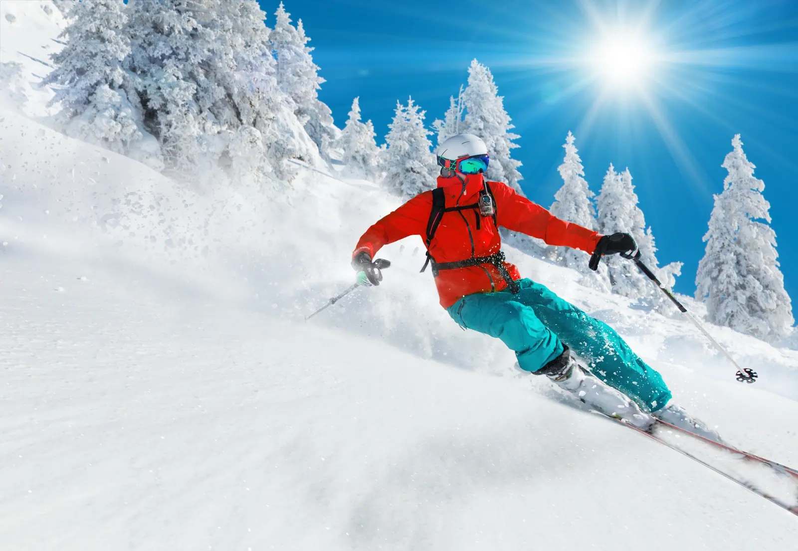 A skier carving through fresh powder under a blue sky